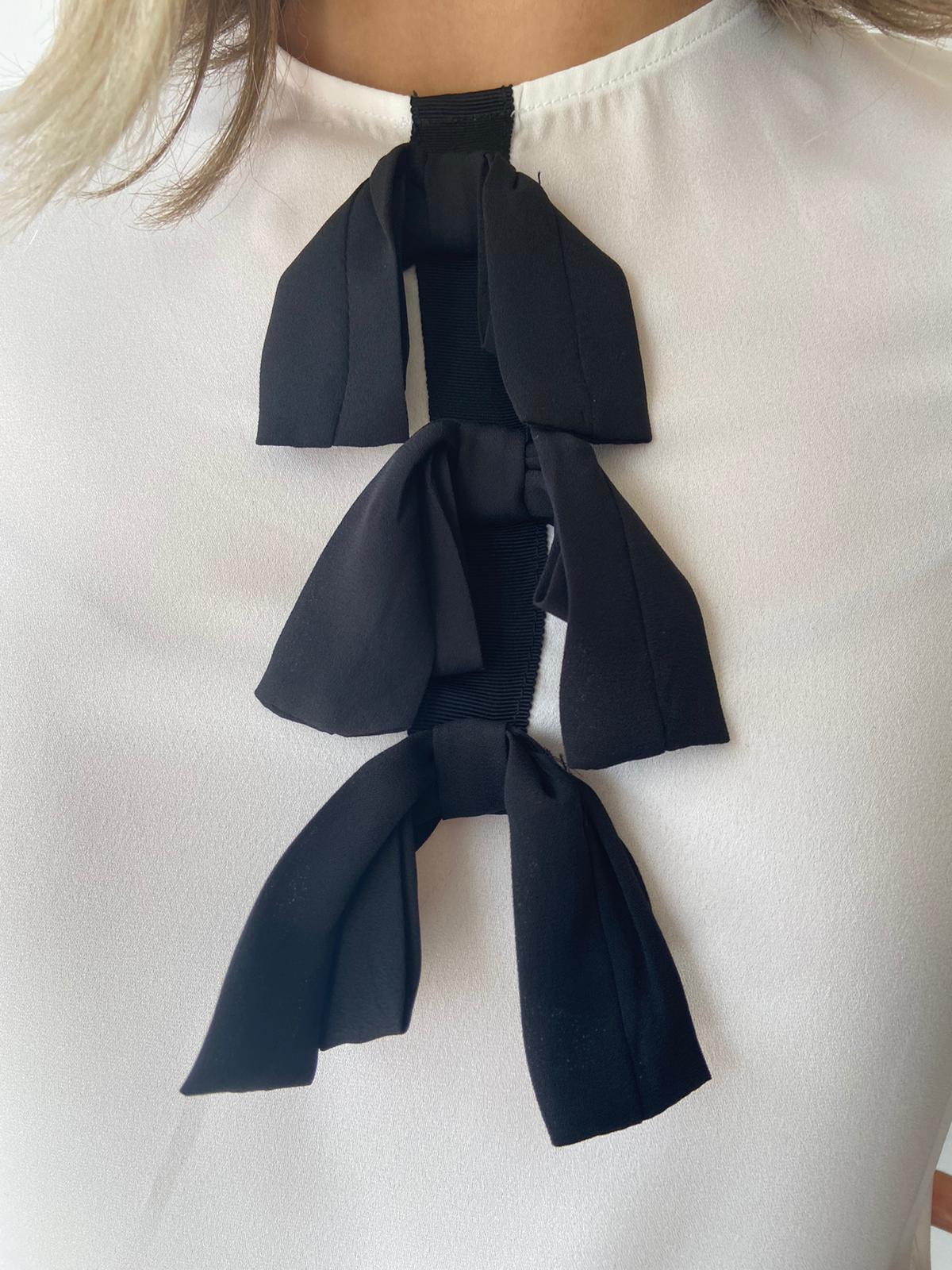 Cream shirt with black bow detail.