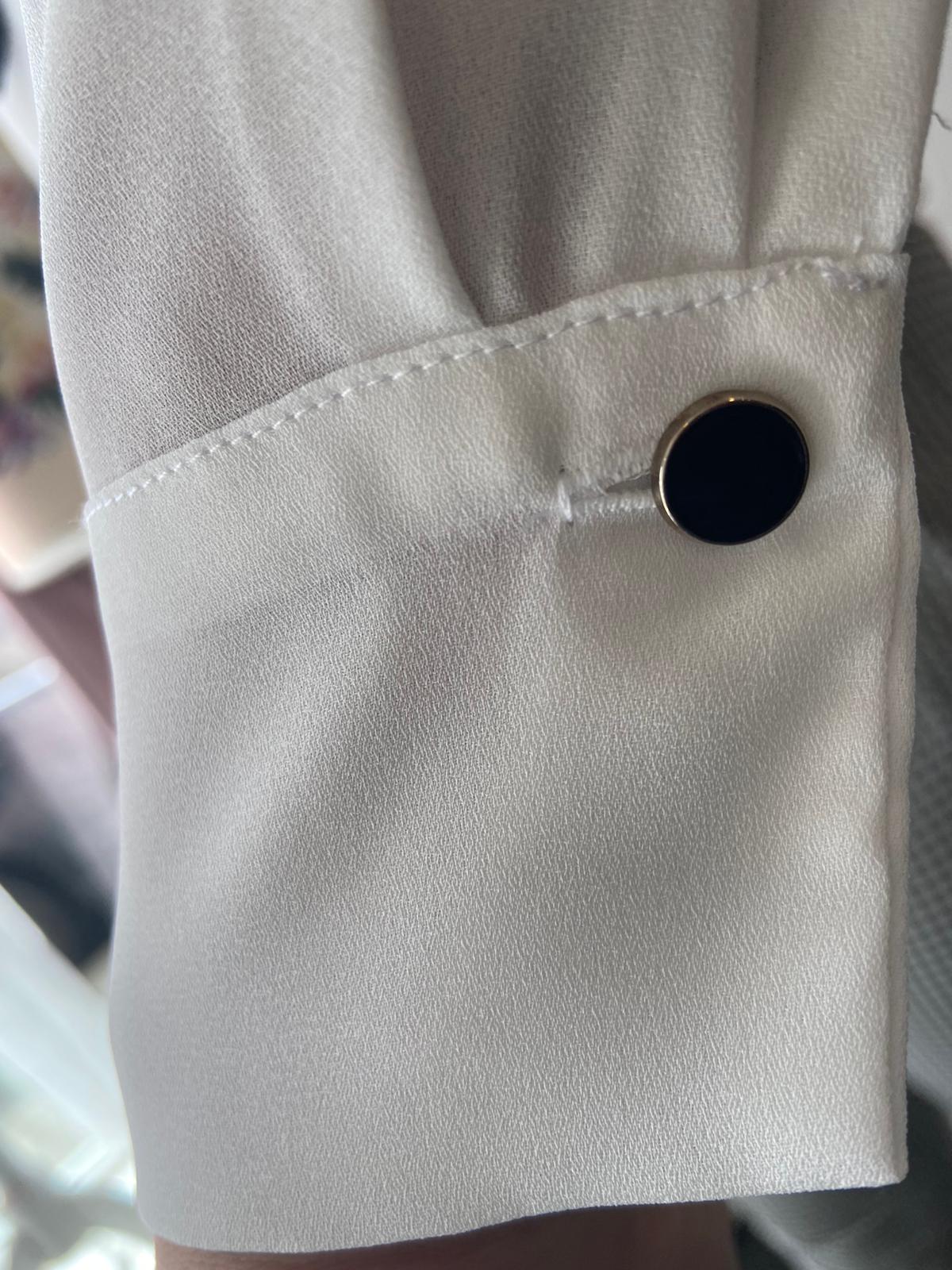 Cream shirt with black bow detail.